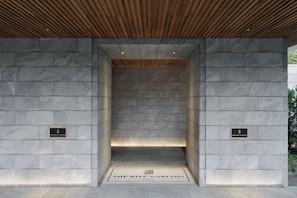 A stone-walled elevator entrance with a plaque reading "The Ritz-Carlton."