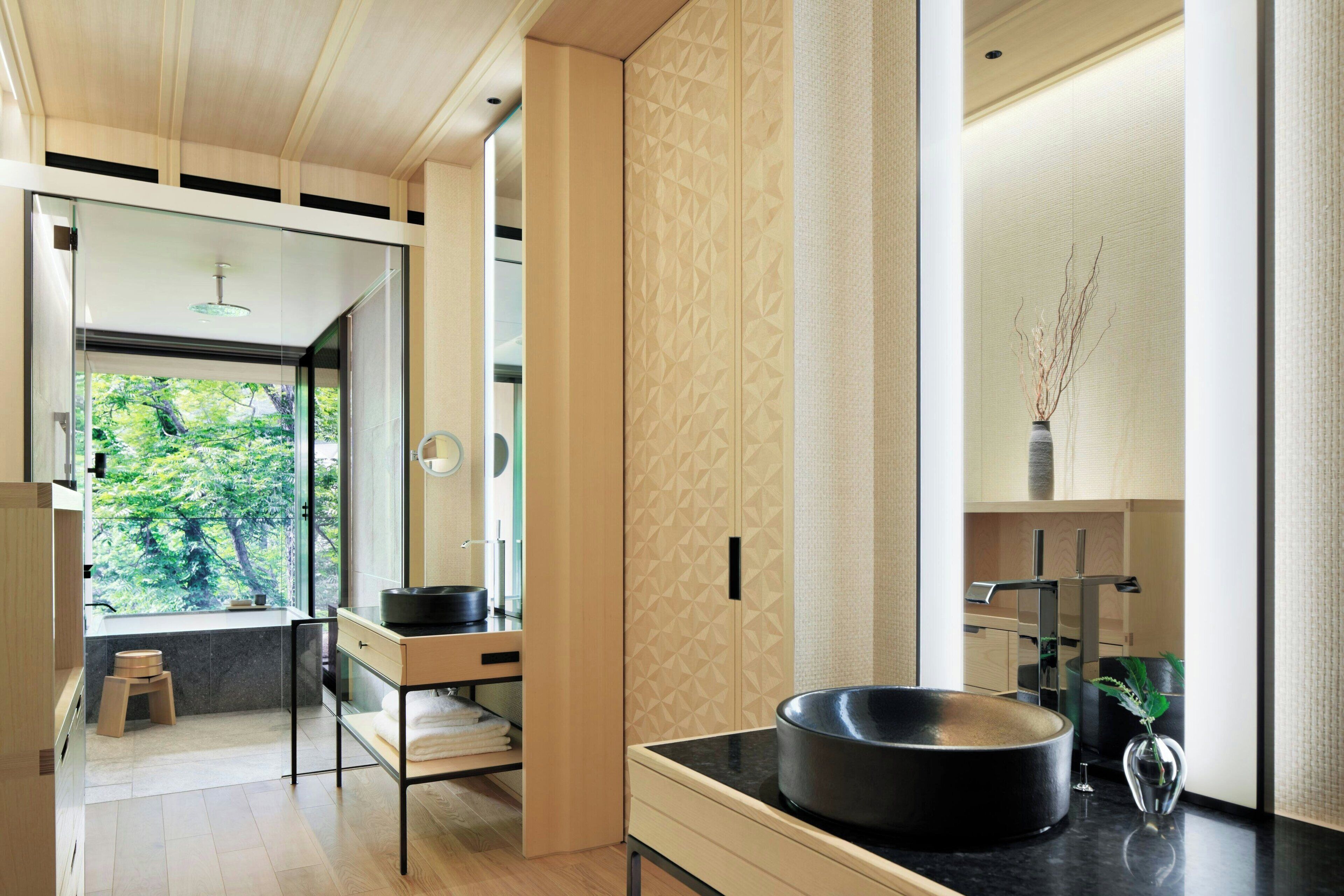 A modern bathroom with a large window, a round sink, and a minimalist design.