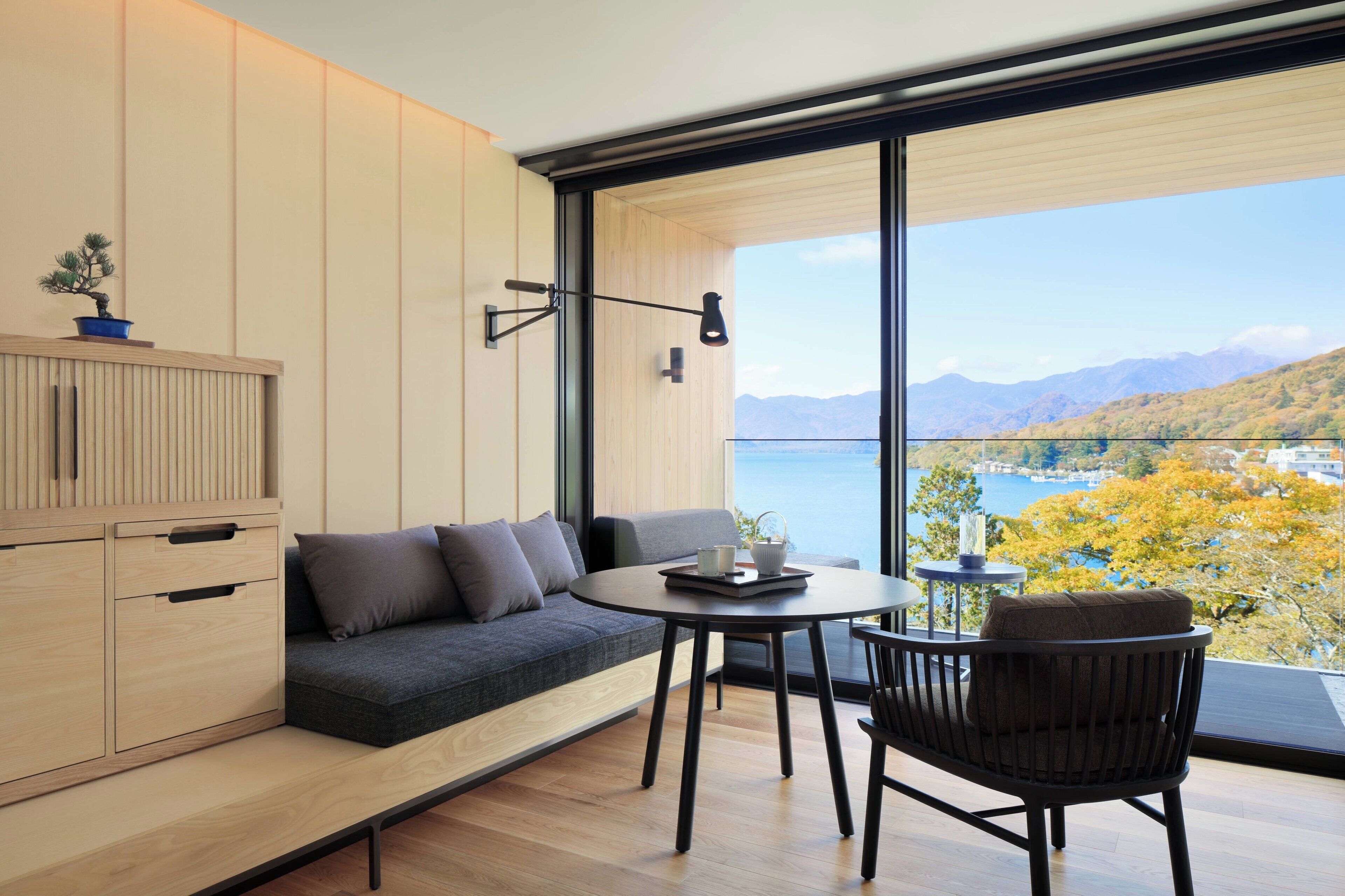 A modern room with a wooden cabinet, a gray sofa, a round table, and a chair.