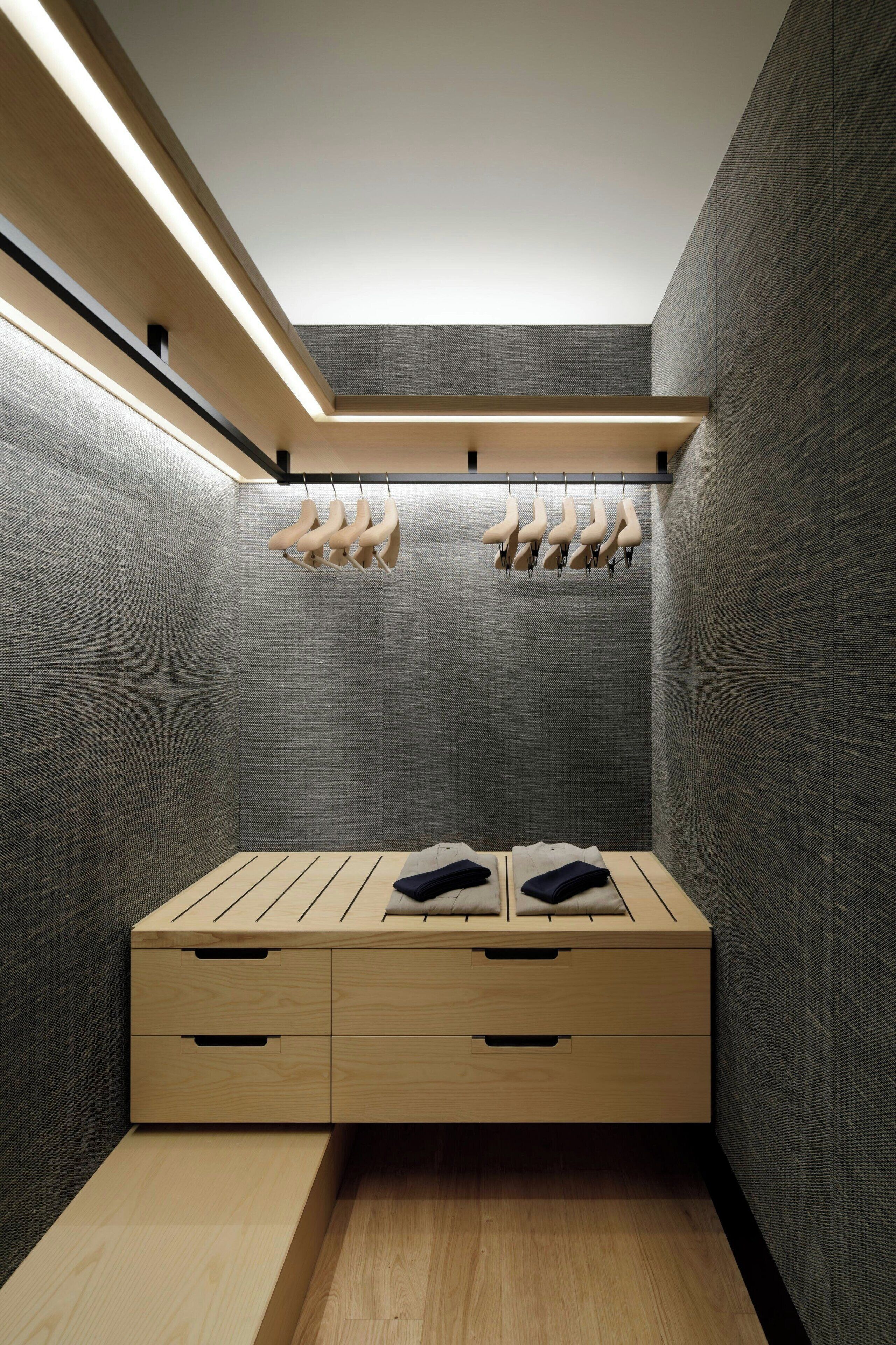 A modern, compact room with a wooden bench, a small wooden table, and a hanging shoe rack.