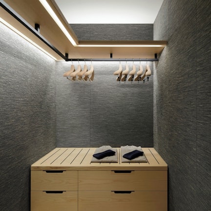 A modern, compact room with a wooden bench, a small wooden table, and a hanging shoe rack.
