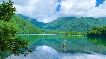 Um lago tranquilo rodeado por montanhas verdes e exuberantes sob um céu parcialmente nublado.
