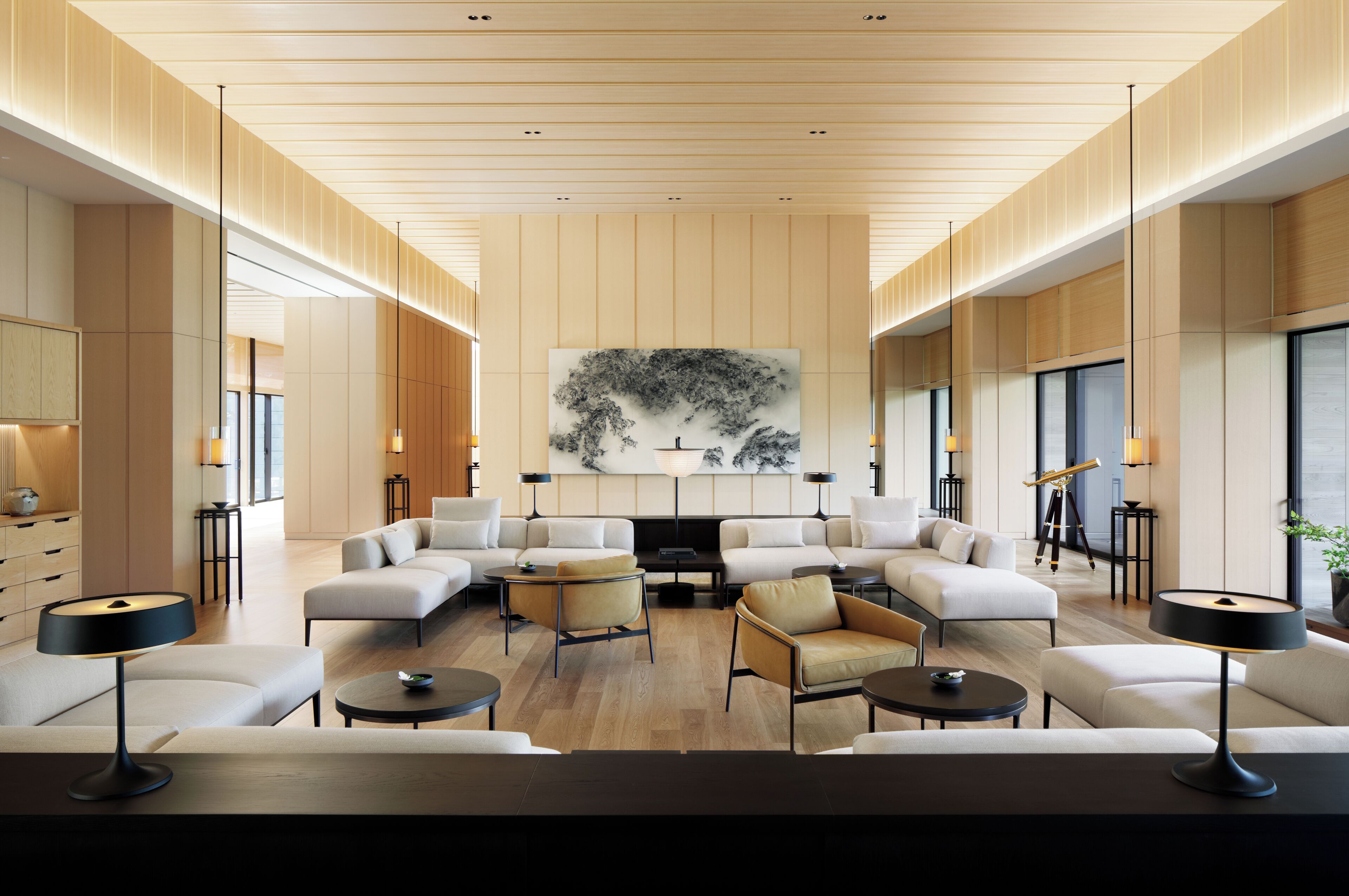 A spacious living room with a large sectional sofa, a coffee table, and a flat-screen TV. There are two side tables with lamps, and a large abstract painting on the wall.