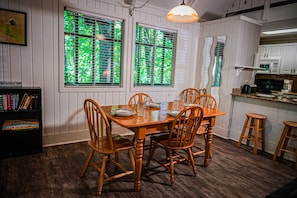 Cozy dining area with a table for four, bookshelf, and kitchenette.
