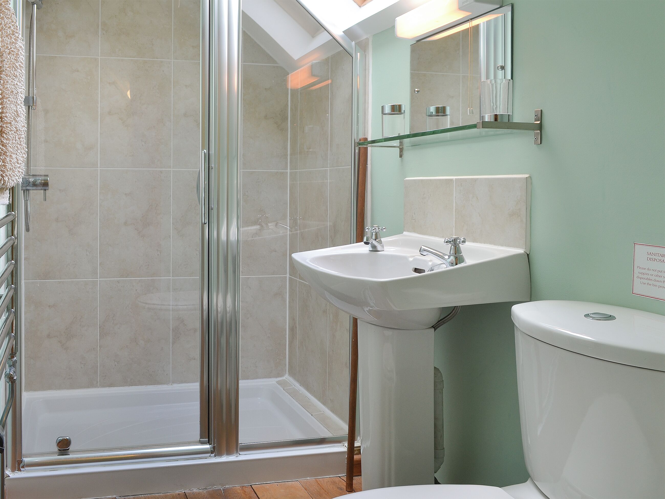 Un baño con cabina de ducha de vidrio, lavamanos blanco y retrete.