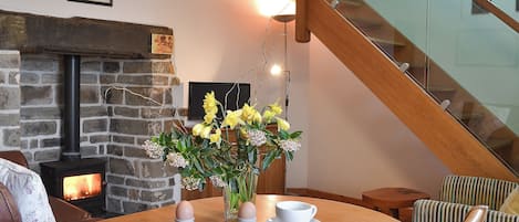 A dining area with a fireplace, a staircase, and a table set for two.