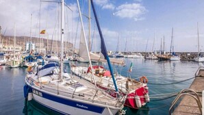 A marina with multiple sailboats docked, a clear sky, and a distant shoreline. - GRAN CANARIA HOME (7), ARGUINEGUIN BEACH AND SUN (Arguineguin)