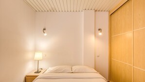 A bedroom with a bed, bedside table, lamp, and wooden wardrobe. - GRAN CANARIA HOME (7), ARGUINEGUIN BEACH AND SUN (Arguineguin)