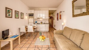 A compact living space with a kitchenette, a dining area with chairs, a sofa, and a TV. - GRAN CANARIA HOME (7), ARGUINEGUIN BEACH AND SUN (Arguineguin)