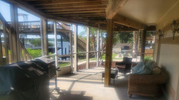 Un espacio al aire libre cubierto con una parrilla, muebles de mimbre y vistas a un muelle y al agua.