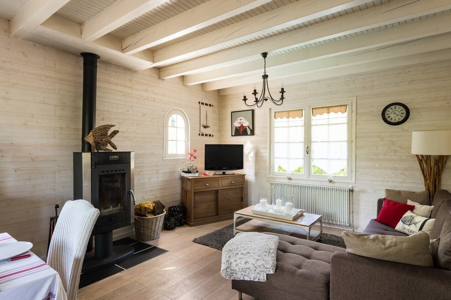 Una sala de estar acogedora con chimenea, paredes de madera, un sofá, un televisor y una araña.
