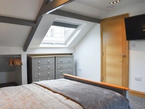 A bedroom with a skylight, a wardrobe, and a bed with a blanket.