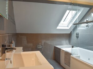 A modern bathroom with a large bathtub, a glass shower enclosure, and a skylight.