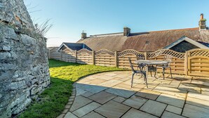A stone wall, a wooden fence, and a patio with a table and chairs.