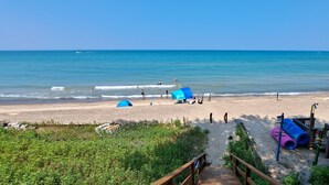 Una spiaggia con tende, un pontile di legno e una vista libera sull'oceano.