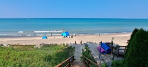 Una playa con tiendas de campaña, una terraza de madera y una vista despejada del océano.