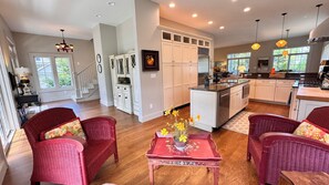 A spacious kitchen with white cabinets, a central island, and a dining area with wicker chairs.