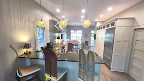 A modern kitchen with granite countertops, stainless steel appliances, and pendant lighting.