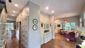 A spacious living area with a staircase, a dining area, and a kitchen with white cabinets.
