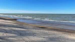Una spiaggia con un litorale sabbioso e onde.