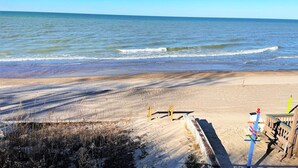 Una spiaggia sabbiosa con una recinzione in legno e una panchina.