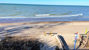 Una playa arenosa con una valla de madera y un banco.