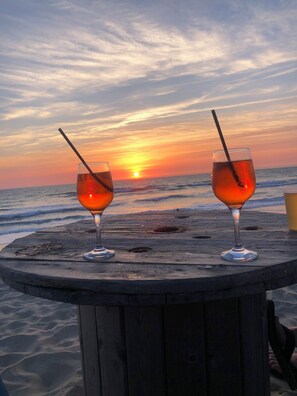 Two glasses of red beverage on a wooden table with a sunset view. - ATLANTIC VILLA (Soulac-sur-Mer)