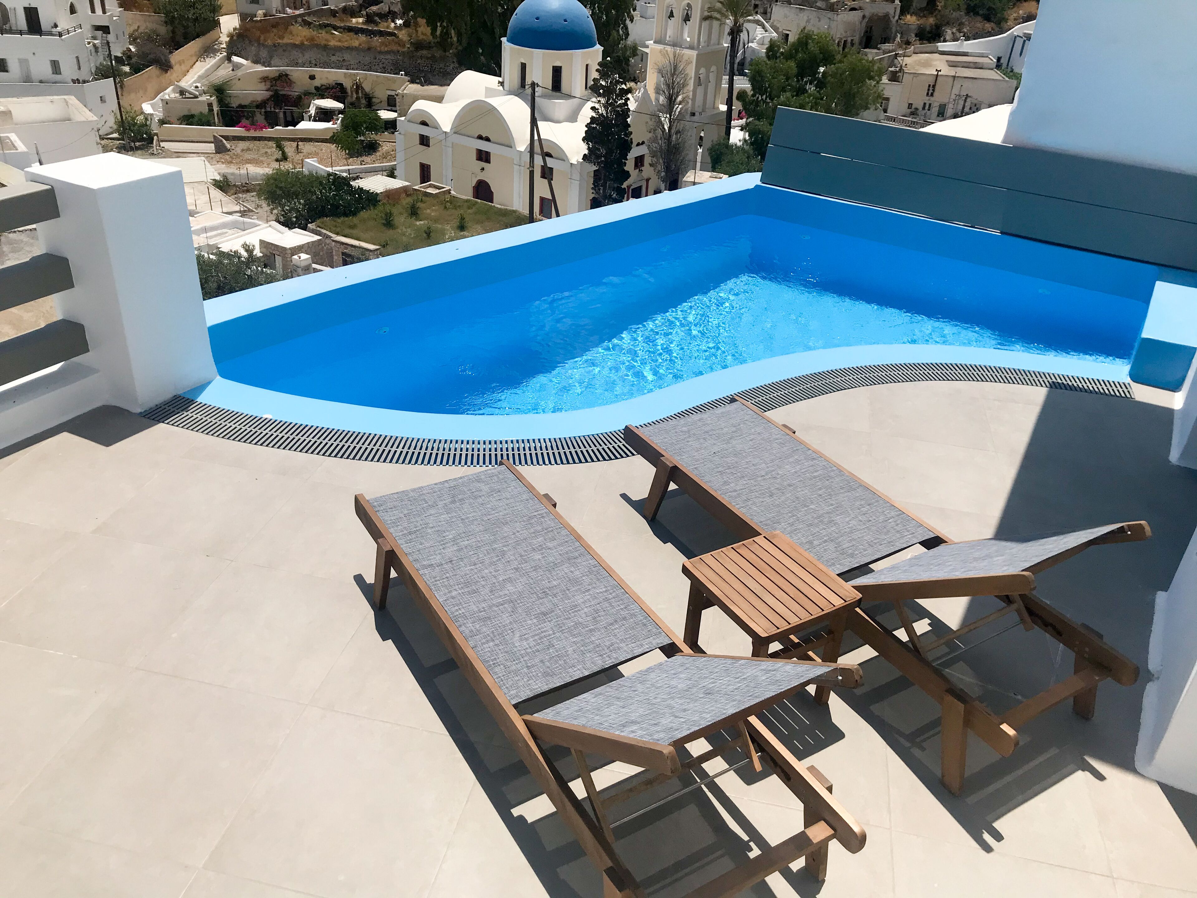 Una piscina sul tetto con superficie d'acqua cristallina, circondata da sdraio e un pavimento piastrellato.
