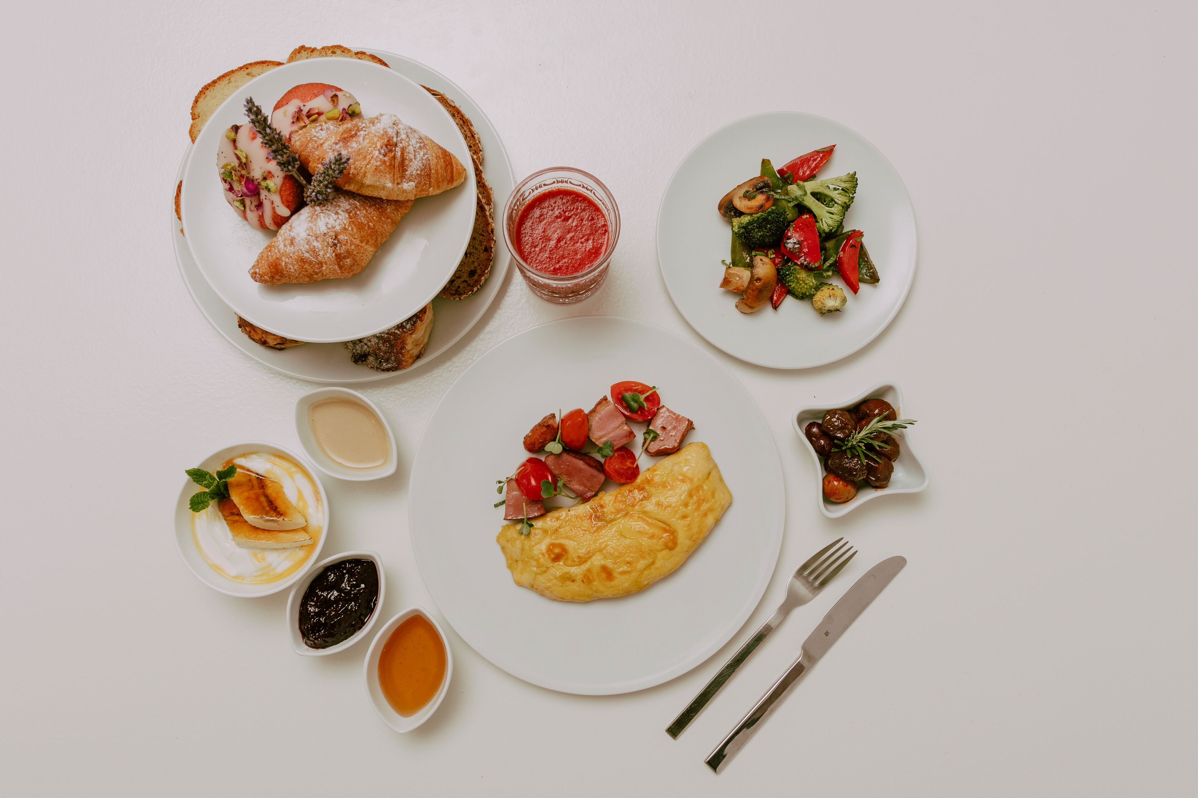 Une table où l’on trouve divers plats, notamment des croissants, une omelette et une salade.