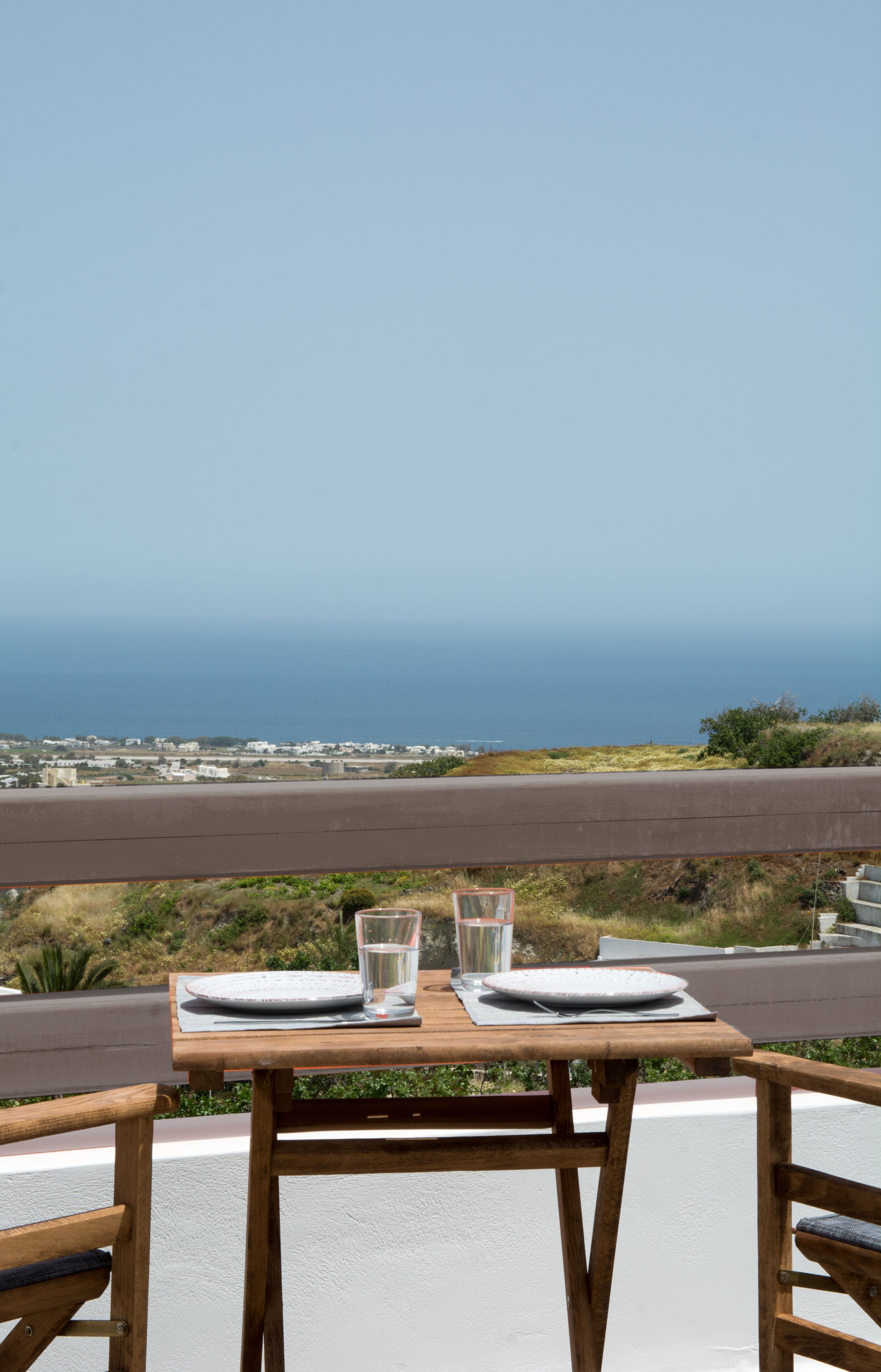 Une table avec un verre d’eau et une assiette, donnant sur une vue sur la côte.