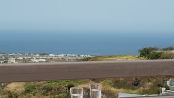 Une table avec un verre d’eau et une assiette, donnant sur une vue sur la côte.