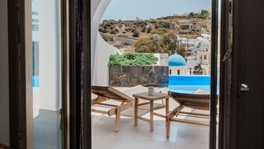 A room with a view of a blue-domed building and a hillside. - Amphitrite Suites Santorini (Santorini)