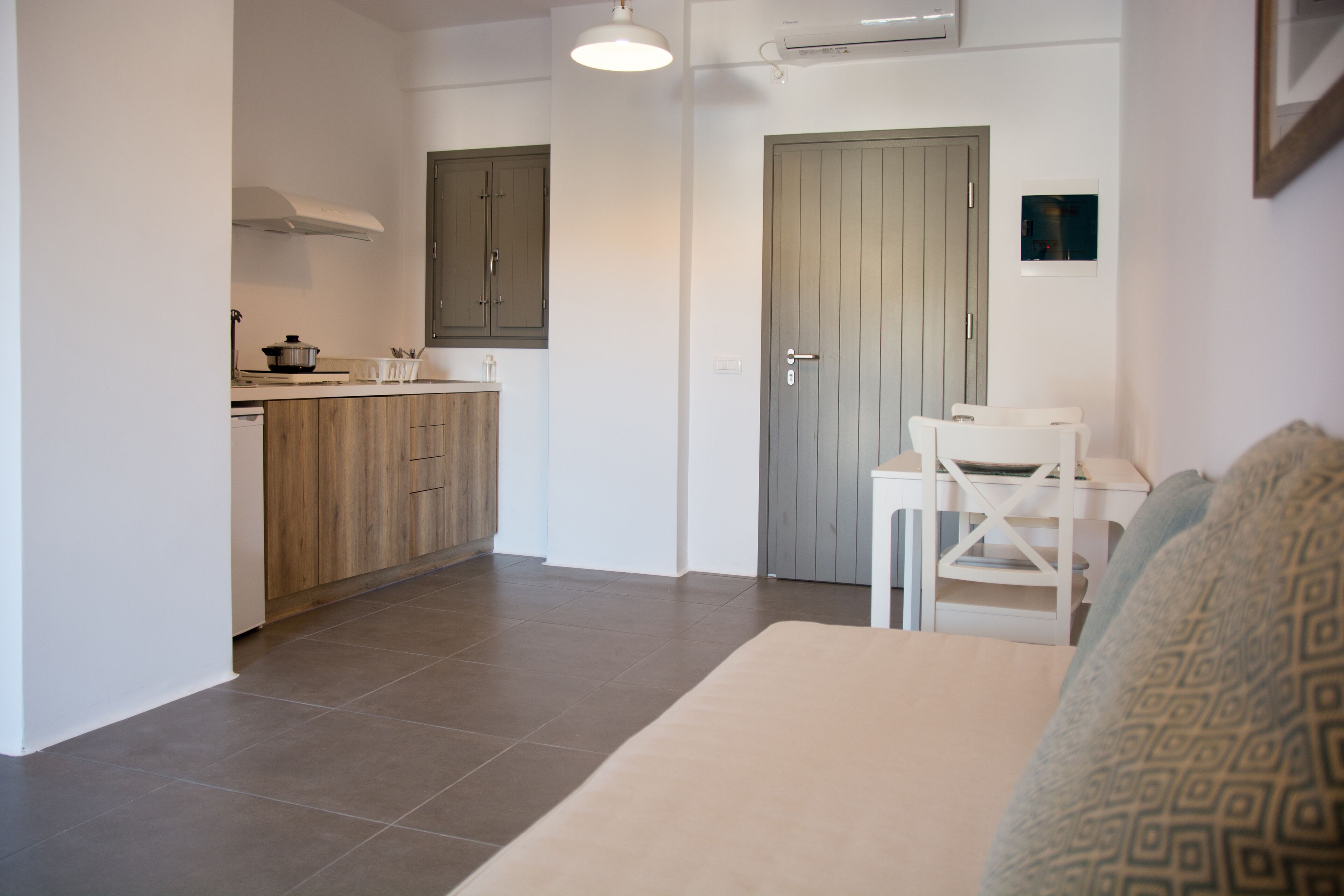 Un espacio habitable compacto con kitchenette, comedor y una puerta que da a otra habitación.