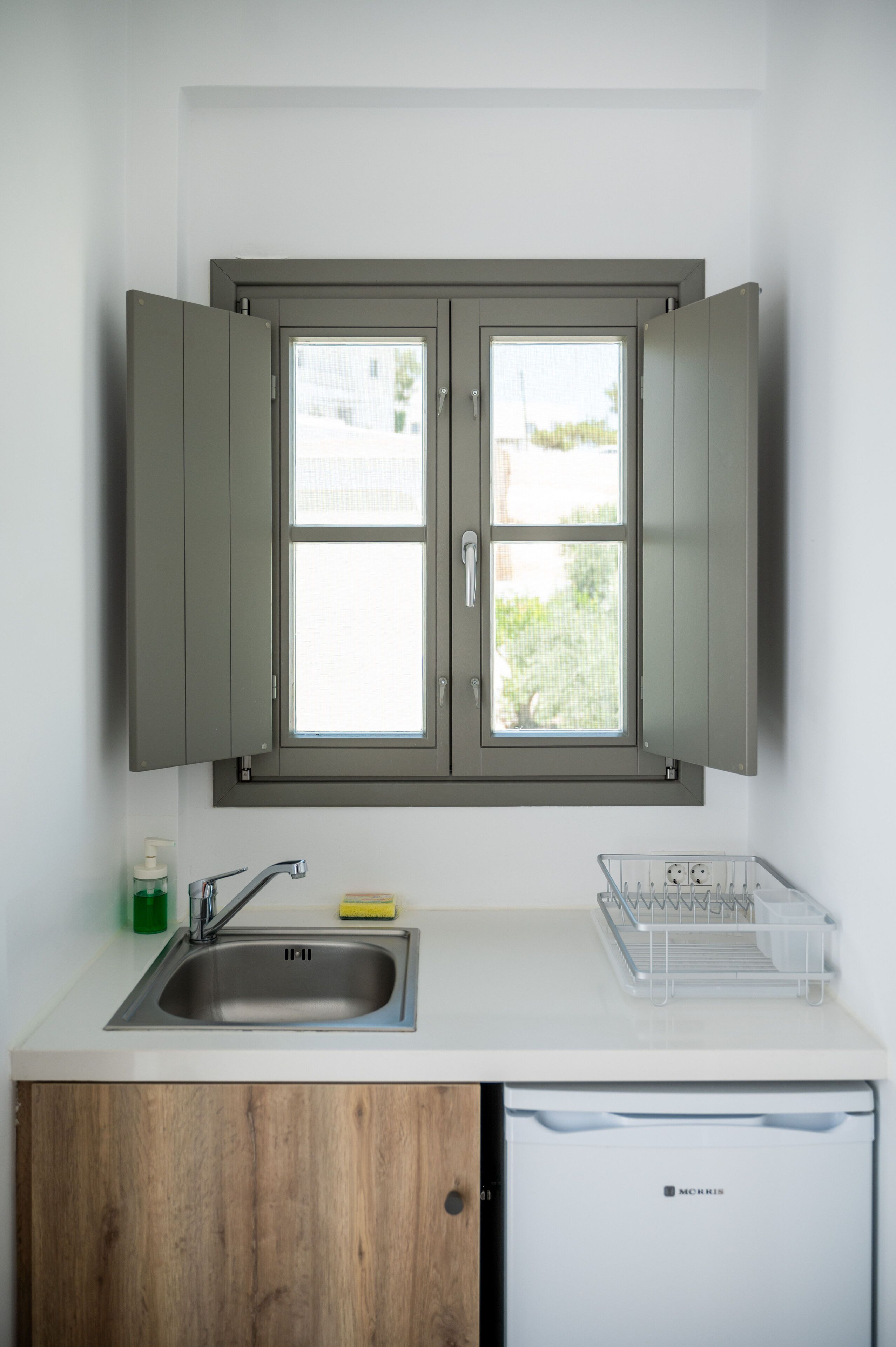 A kitchen with a double sink, a window, and a dishwasher.