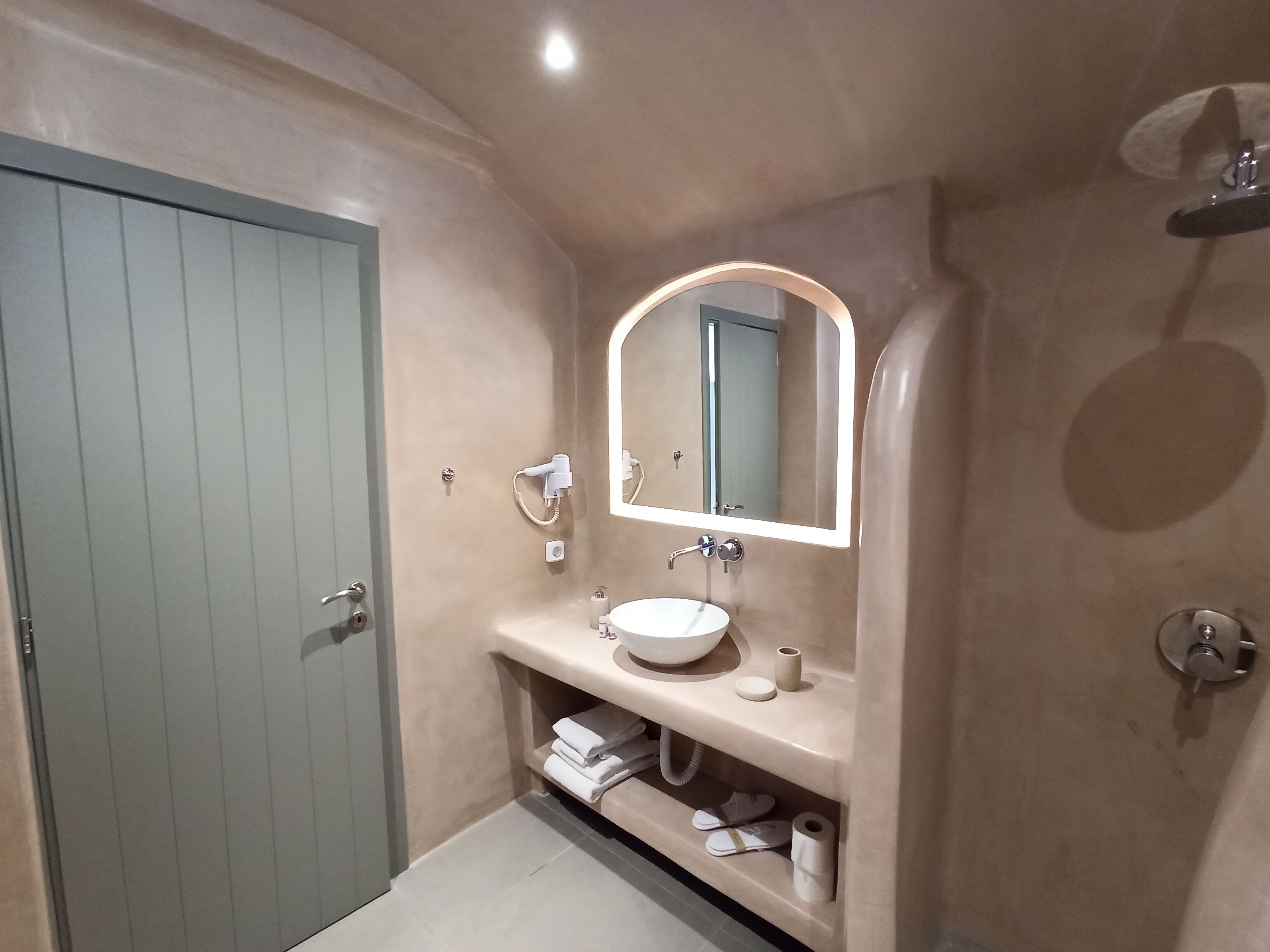 A bathroom with a sink, mirror, towel rack, and a shower area.