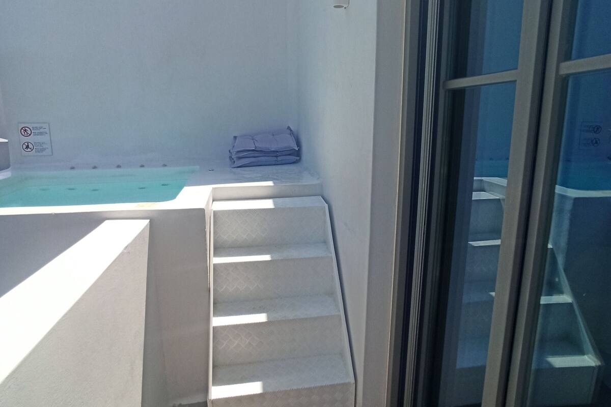 A balcony with a pool, a set of stairs, and a sliding glass door.