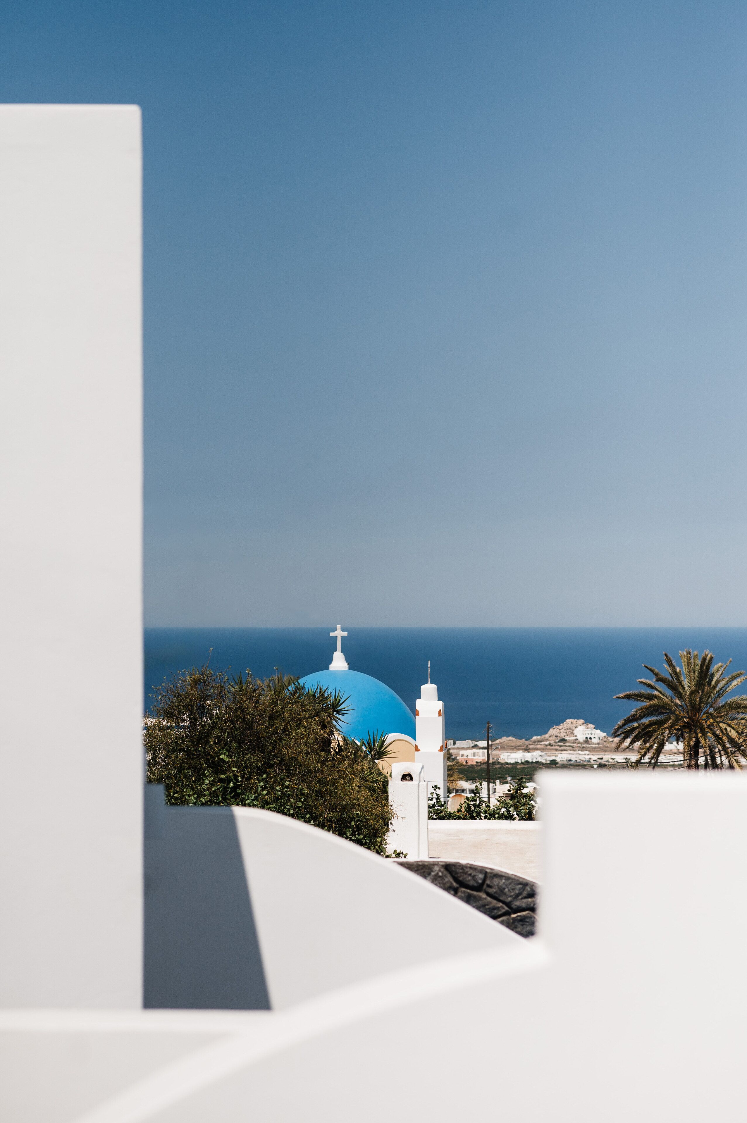 Vista costeira com um edifício branco, uma cúpula azul e uma torre branca.