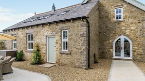 A stone building with a tiled roof, a door, and a window.