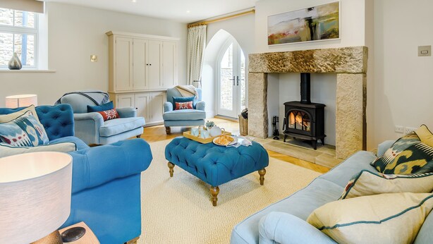 A living room with a stone fireplace, blue sofas, and a large window.