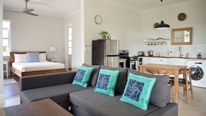 En moderne og lys stue med sofa, seng, spiseplads og køkken.