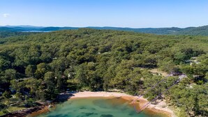 Paisaje costero con un bosque denso, una playa de arena y una vista despejada del mar.