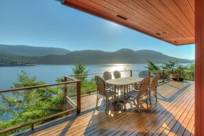 A wooden deck with a table and chairs overlooking a lake and mountains. - Waterfront! - Incredible views; Private beach; Spa (Eastsound)