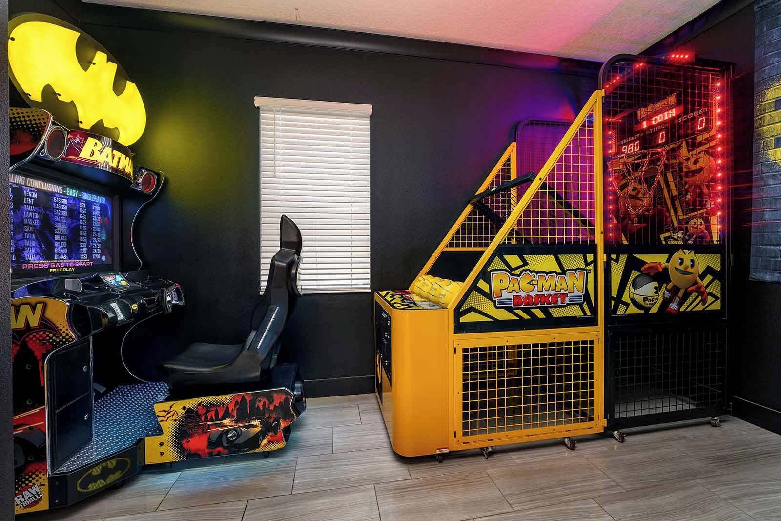 Een speelruimte met een Batman-arcadekast, een Pac-Man spel en een zwarte gaming stoel.