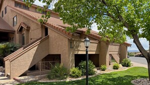 Un bâtiment à deux étages, avec une façade en stuc, un toit en tuiles et un jardin bien aménagé à l’avant, comprenant une pelouse bien entretenue et un lampadaire.