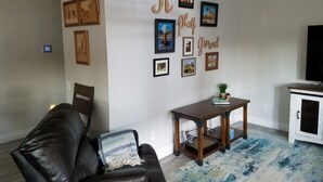Una sala de estar con un sofá de cuero, una mesita de madera y un mueble para la televisión.