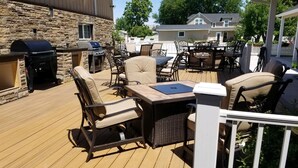 Una terraza al aire libre con mobiliario de mimbre, una parrilla y una mesa.