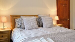 Et soveværelse med en seng, to sengeborde, en trædør og et natbord med lampe.
