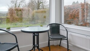 Et hjørneværelse med vindue, et rundt bord og to stole.