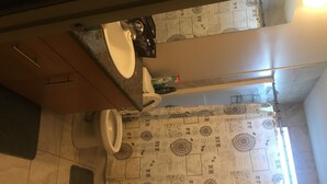 A bathroom with a toilet, sink, and a patterned shower curtain. - Bridgeland - central (Calgary)