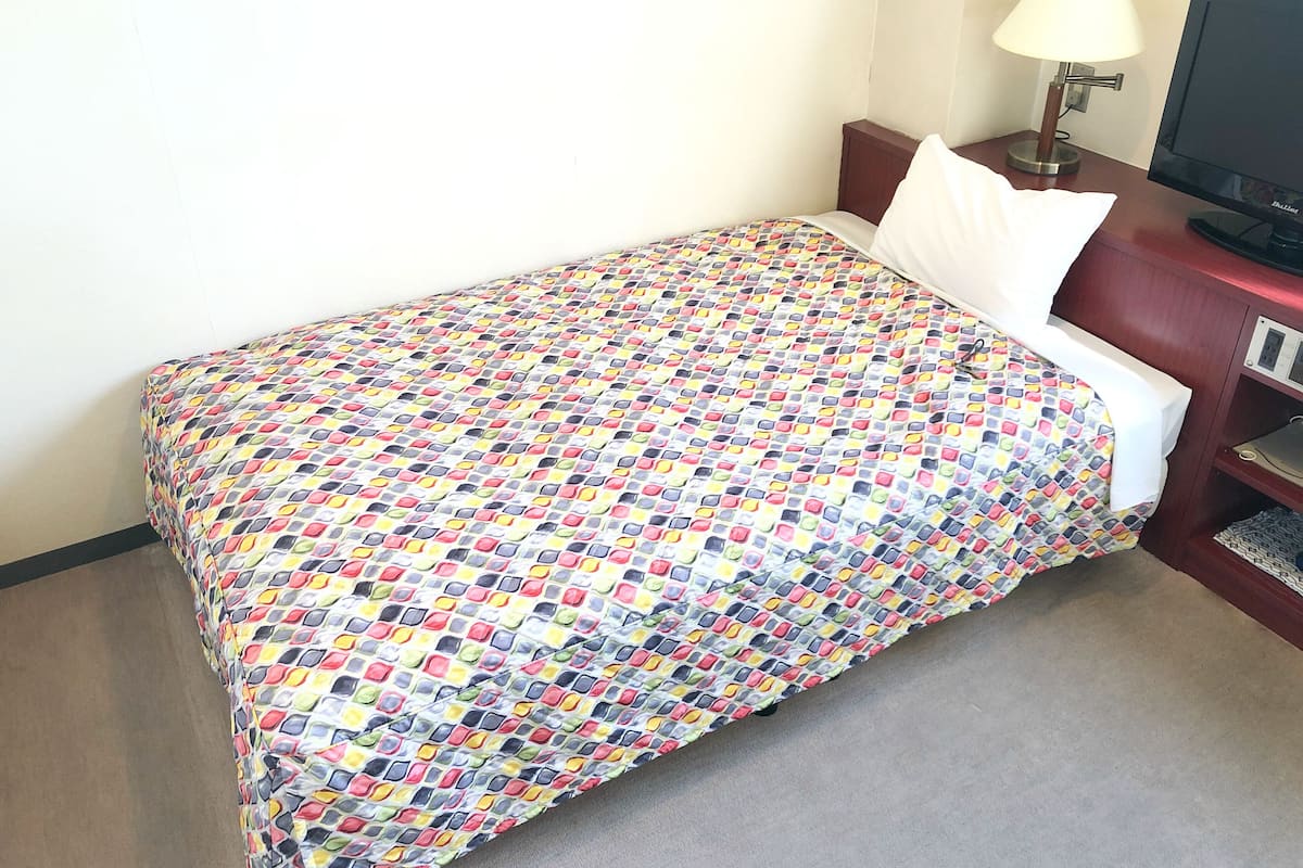 Una habitación de hotel con cama, escritorio con lámpara y televisión.